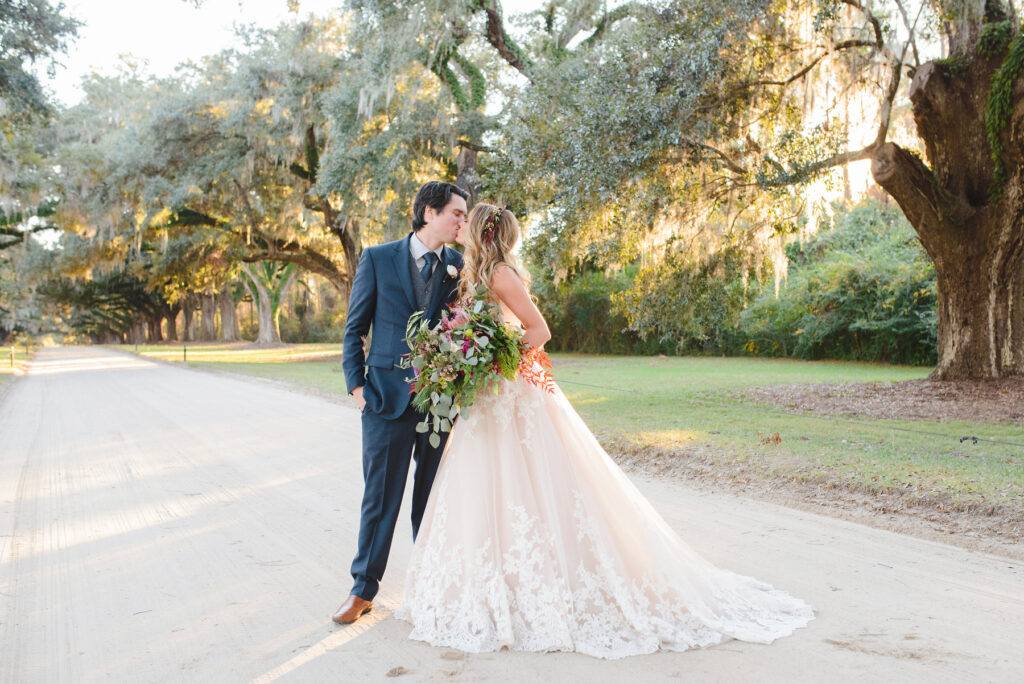 A bride and groom kiss for a portrait after their winter side lawn Boone Hall wedding ceremony.