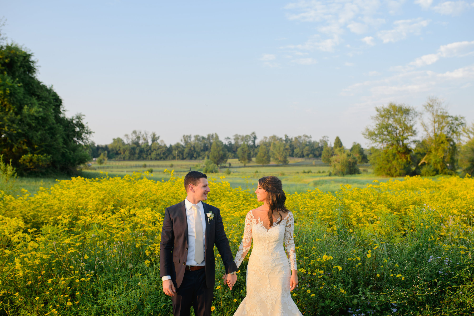 A groom and bride pose in a sunflower field during their fall Salamander Resort wedding in Virginia.