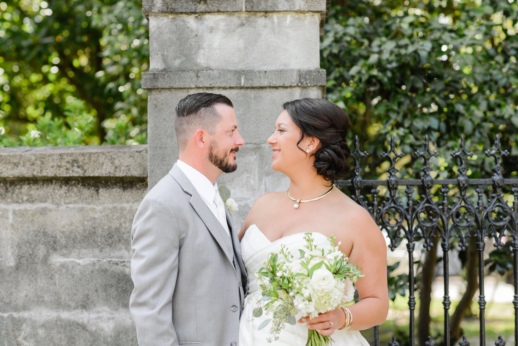 A groom and bride pose for a wedding photo during their gold pink and navy Lowndes Grove wedding.