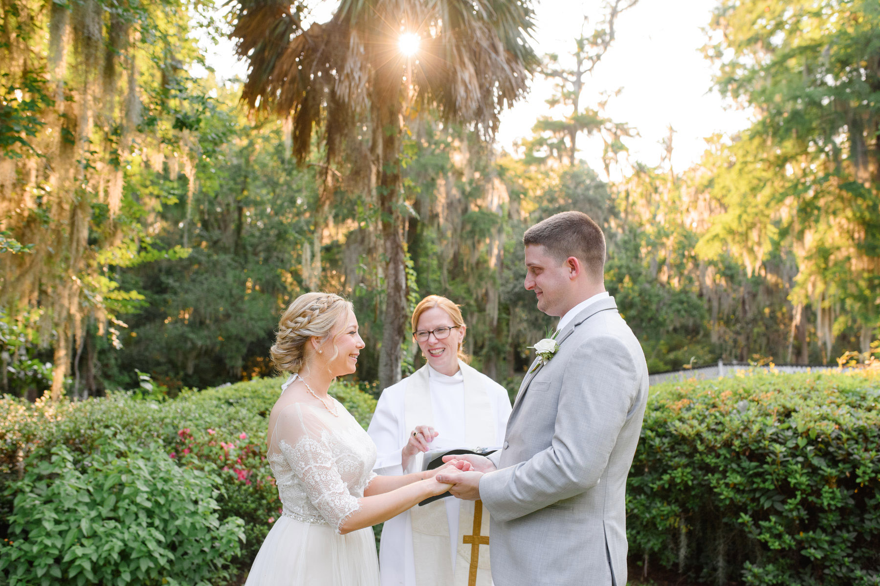 A woman and man eloping in Charleston are exchanging rings with the officiant watching