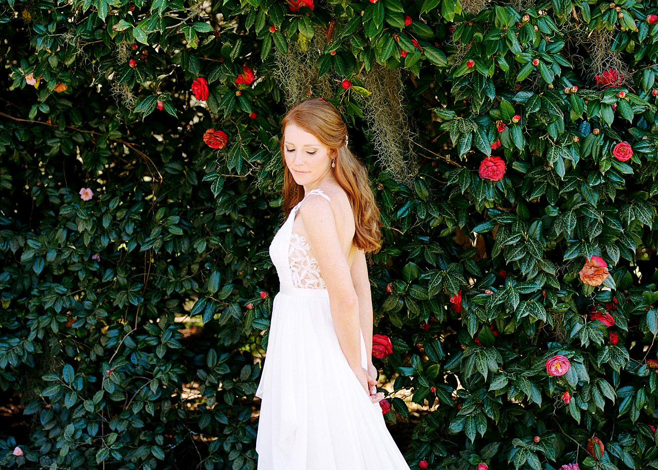 A bride poses for a portrait in front of a blooming bush at Legare Waring House